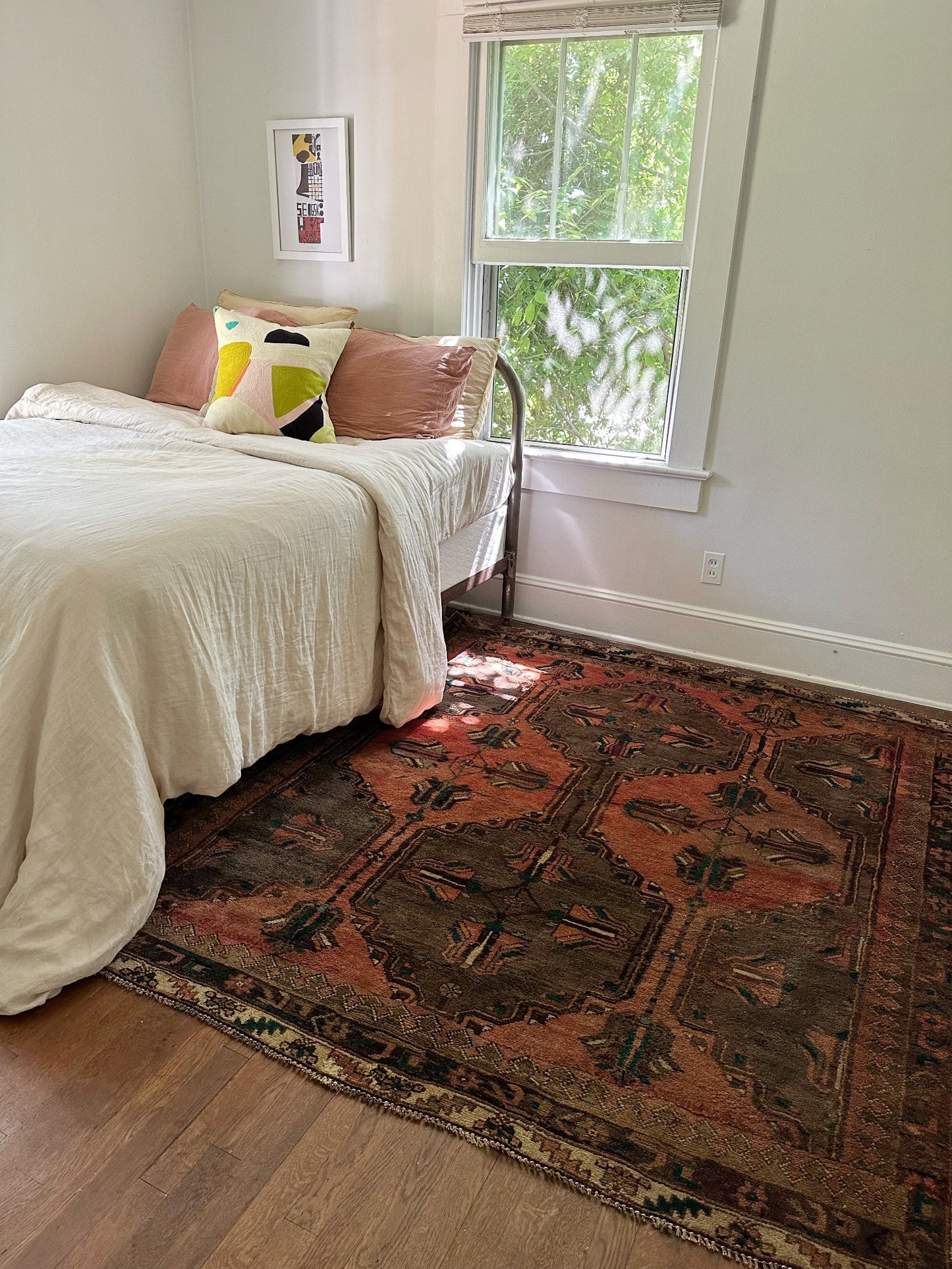 Copper Persian rug looks so inviting in a bright bedroom in the afternoon.
