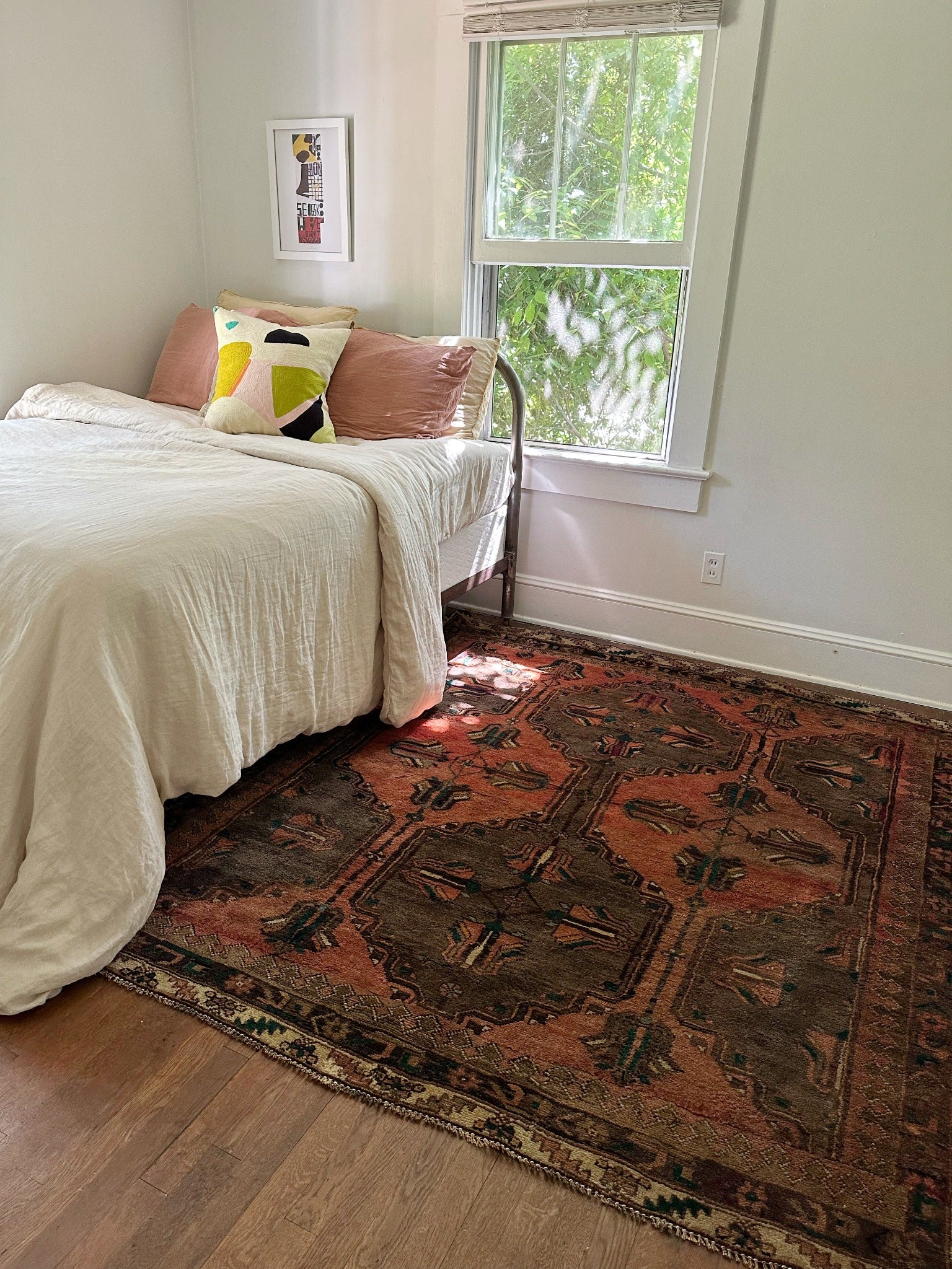 Copper Persian rug looks so inviting in a bright bedroom in the afternoon.