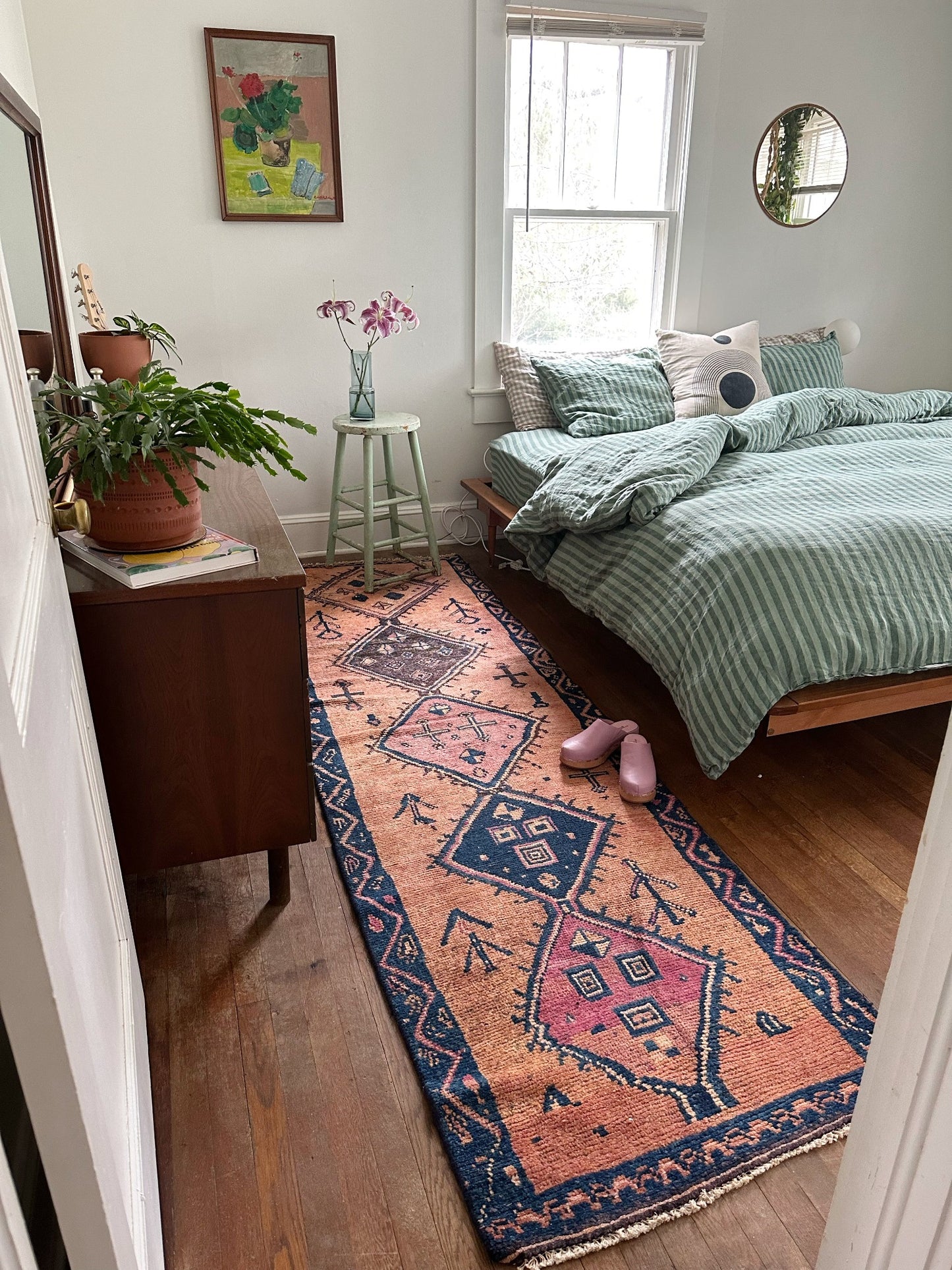 Pink rug styled next to bed. Vintage runner rug