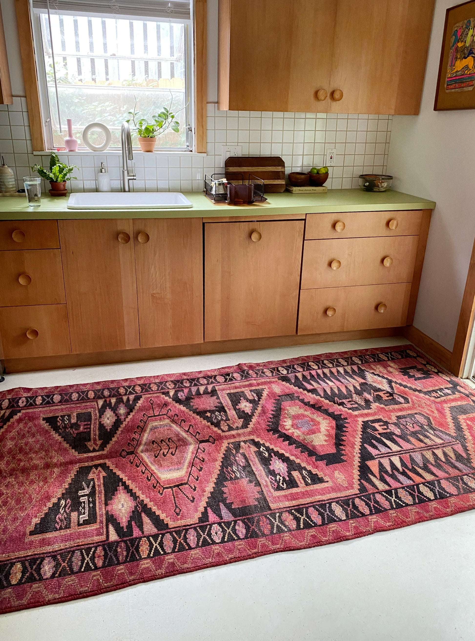 The kitchen is graced by a charming Persian rug, infusing the space with lively color accents